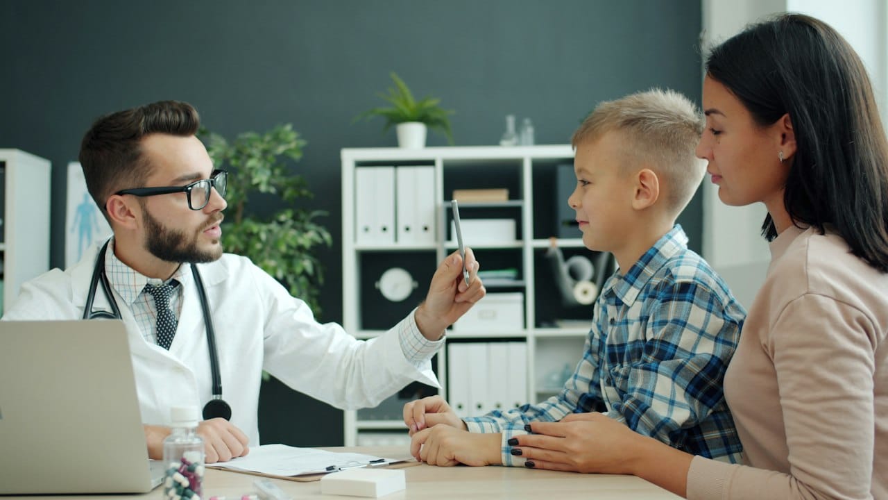 Annesinin yanında çocuğu muayene eden doktor