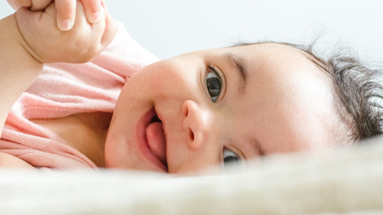 Yatakta uzanan gülümseyen bebek