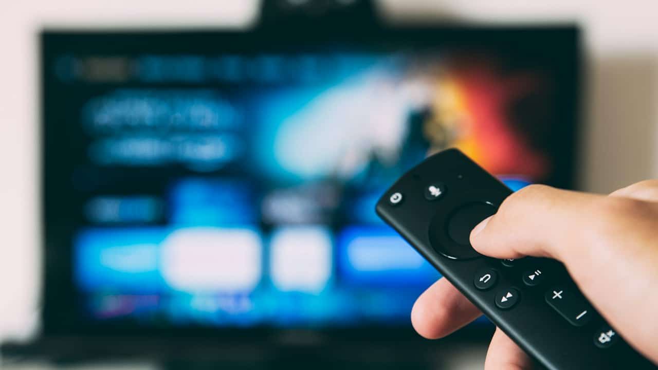 Televizyon karşısında kumanda tutan el