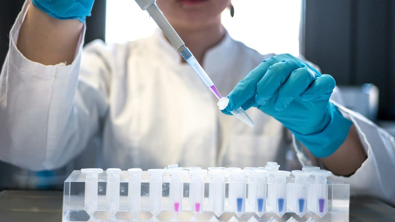 Laboratuvarda pipetle deney tüplerine sıvı aktaran bilim insanı