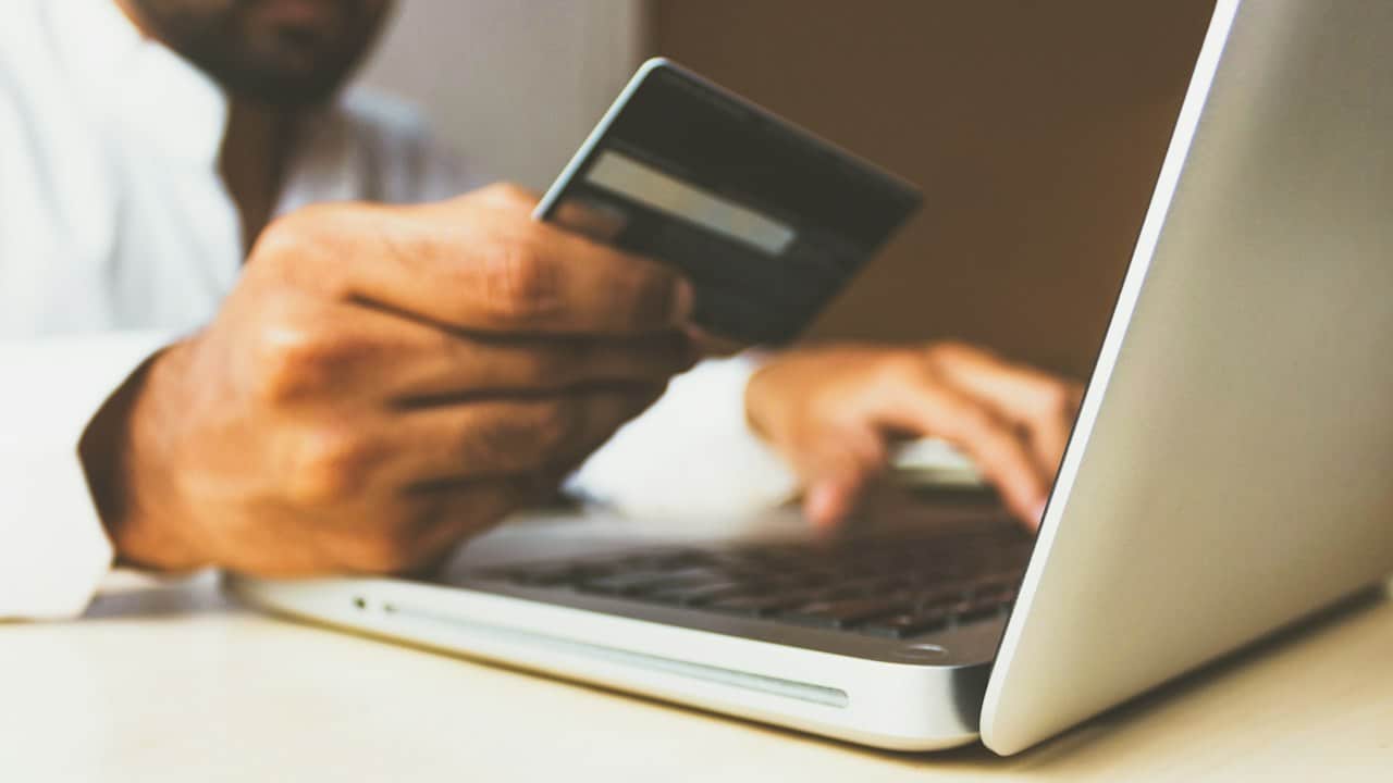 Elinde banka kartıyla bilgisayardan işlem yapan kişi