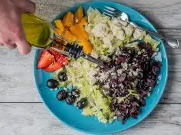 Bitkisel yağlar metabolizmayı nasıl etkiler? Bitkisel yağlar ve metabolik sağlık ilişkisini anlatan, zeytin ve peynirli sebze salatasının üzerine zeytinyağı dökülen tabak