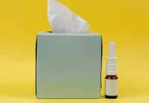 Burun tıkanıklığı döneminde masada duran bir ilaç şişesi ve mendil kutusu