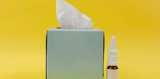 Burun tıkanıklığı için gelişigüzel sprey kullanmak sorunu artırabilir Burun tıkanıklığı döneminde masada duran bir ilaç şişesi ve mendil kutusu