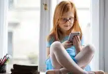 Tek bir fotoğraf çocuğun okulunu ele verebilir: Çocukların dijital mahremiyeti nasıl korunur? Çocukların dijital mahremiyeti açısından odasında akıllı telefonla sosyal medyaya bakan gözlüklü kız çocuğu