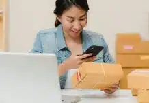 E-ihracat yapmadan önce bu 5 soruya cevap verin E-ihracat siparişlerini dizüstü bilgisayar ve kargo kutuları arasında telefondan kontrol eden bir kadın