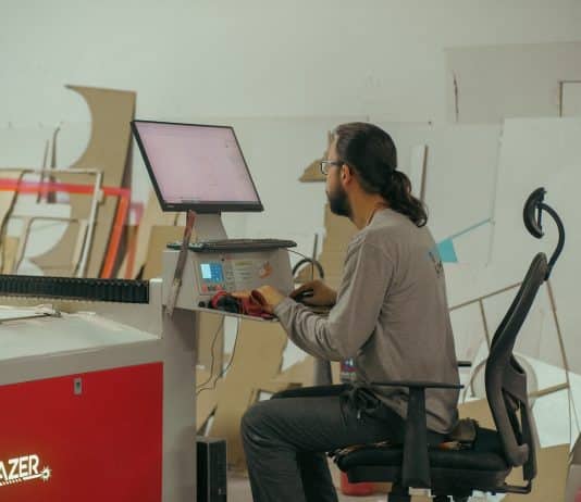 Üretim atölyesinde lazer kesim makinesinin bilgisayarında çalışan genç çalışan; e-ticarette rekabet genç kadrolarla hız kazanıyor
