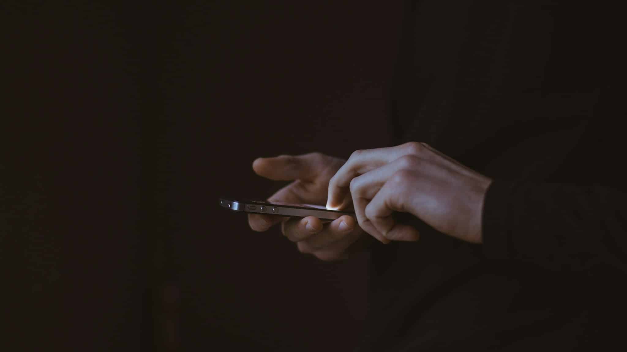 Emoji ile mesajlaşmak için akıllı telefon kullanan kişinin silueti