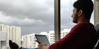Evde pencere önünde tabletine bakan genç adam; ev gençliği Türkiye'de gençlerin dörtte birini kapsıyor