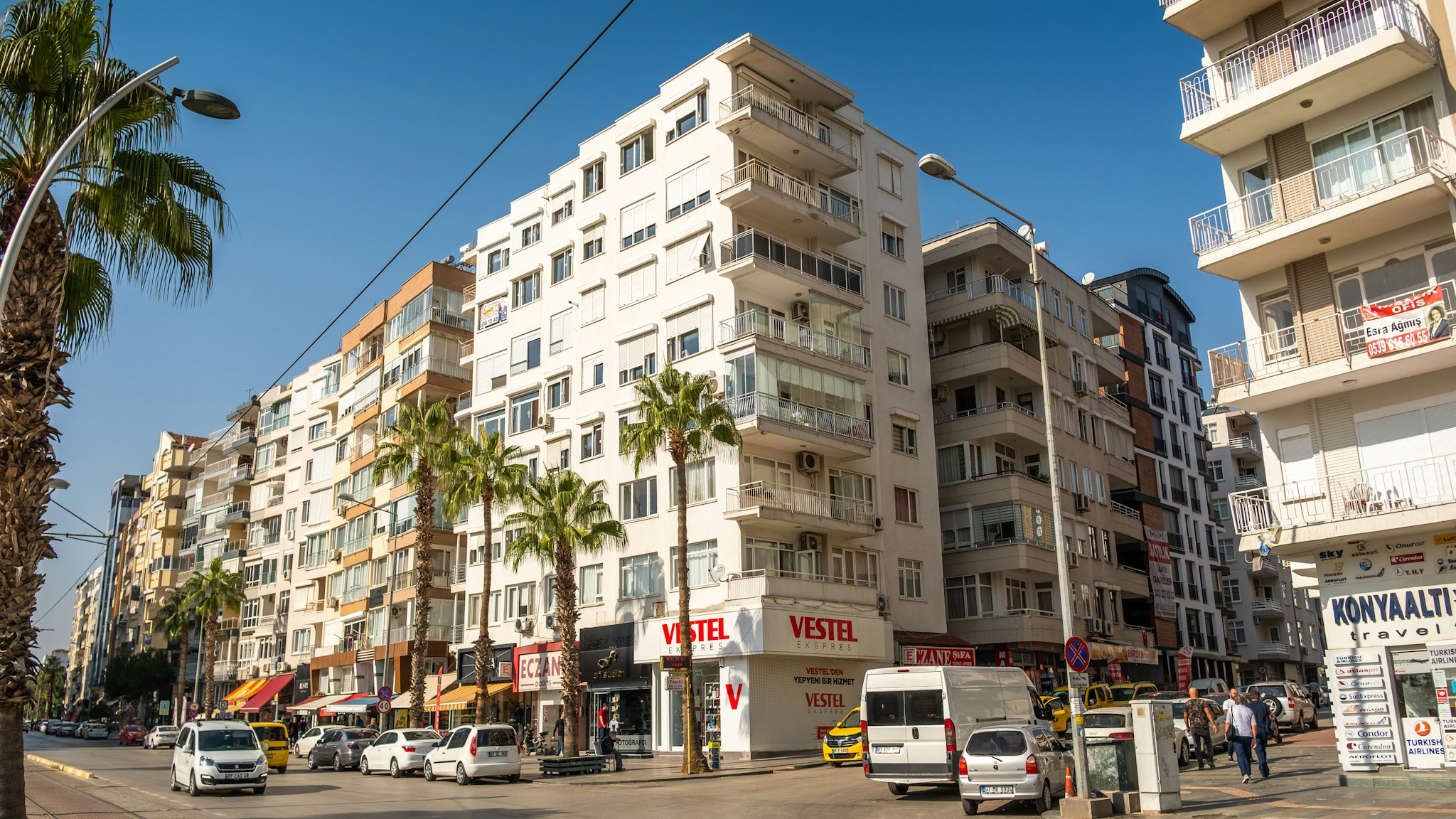 Palmiyeli bir caddede sıralanan apartmanlar; konut yatırımında kira getirisi öne çıkıyor