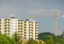 Konut üretimi önünde 3 büyük engel: Finansman, maliyet ve ruhsat Yanında inşaat vinci bulunan sarı balkonlu yeni apartman; konut üretimi finansman, maliyet ve ruhsat engelleriyle karşı karşıya