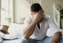 Kristal kayması vertigoya neden olur mu? Yatağın kenarında elini yüzüne kapatan adam, kristal kayması ve baş dönmesi