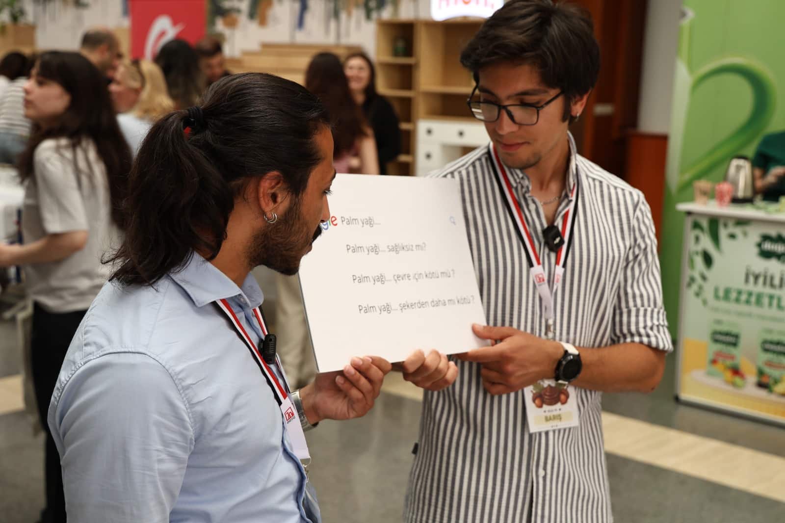 ODTÜ festivalinde iki genç palm yağı sorularının yazılı olduğu kartı tutuyor; palm yağı ve gluten algısı tartışıldı