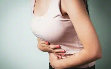 Karnınız yemekten sonra balon gibi şişiyorsa nedeni SIBO olabilir SIBO nedeniyle yemek sonrası karın şişkinliği ve ağrısıyla elini karnına koyan bir kişi