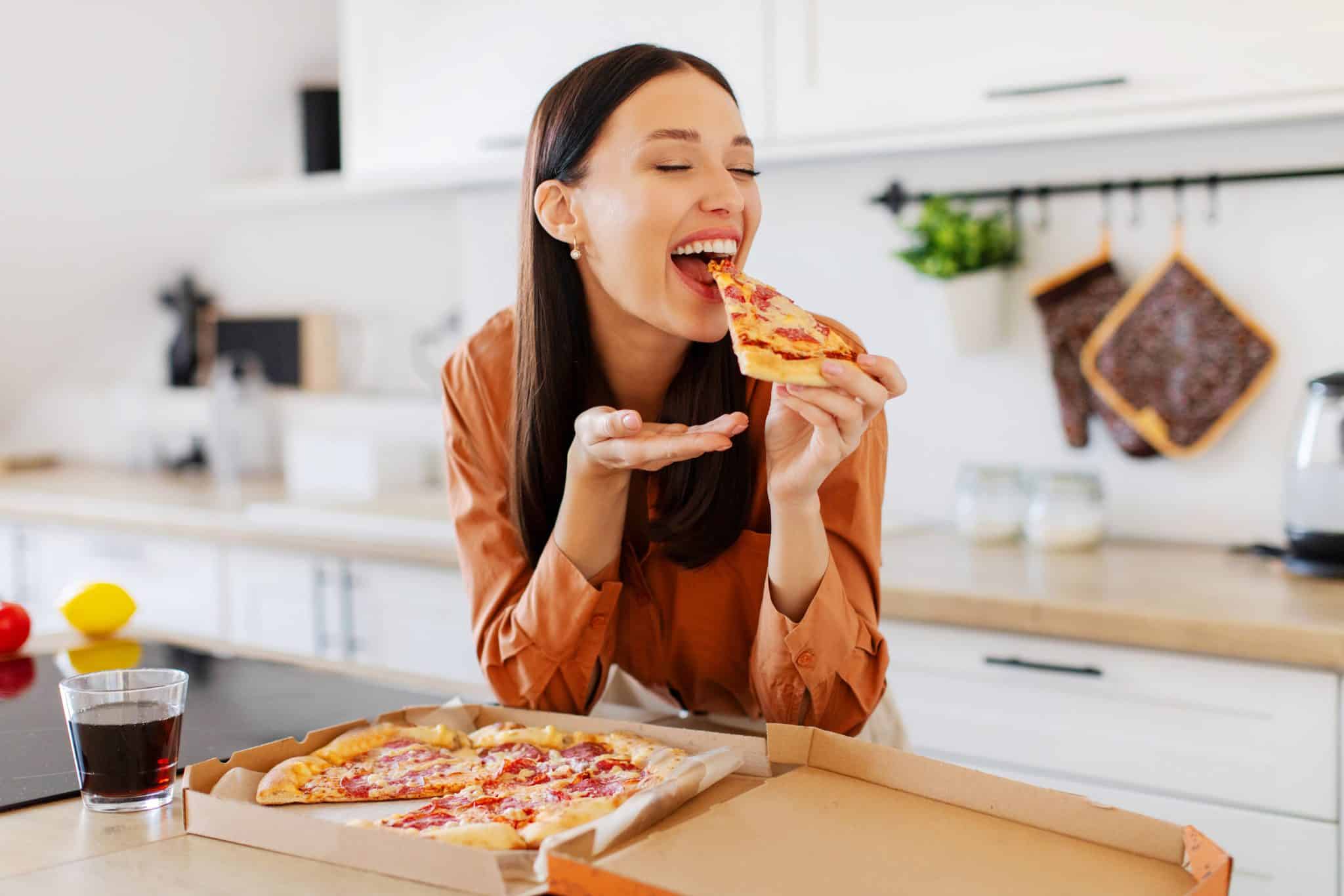 Mutfakta pizza yiyen kadın; sürdürülebilir diyet için duygusal yemeyi fark etmek önemli