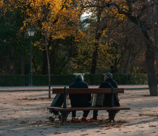 Yaşlanan nüfus: Sonbaharda parkta bankta oturan iki kişi